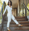 A woman wearing white Bed Stu jeans and Bed Stu sandals on stairs.