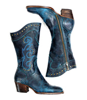 A pair of blue leather, mid-calf cowboy boots called "Limit" by Bed Stu, featuring decorative stitching, metal studs, and side zippers.