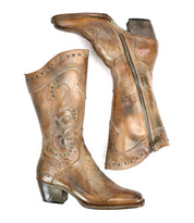 A pair of worn brown leather Bed Stu "Limit" Western mid-calf boots, featuring decorative floral stitching and metal studs. The right boot is shown upright, while the left boot lies on its side with a visible zipper.
