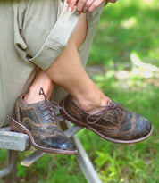 A woman wearing a pair of brown Bed Stu Lita shoes.