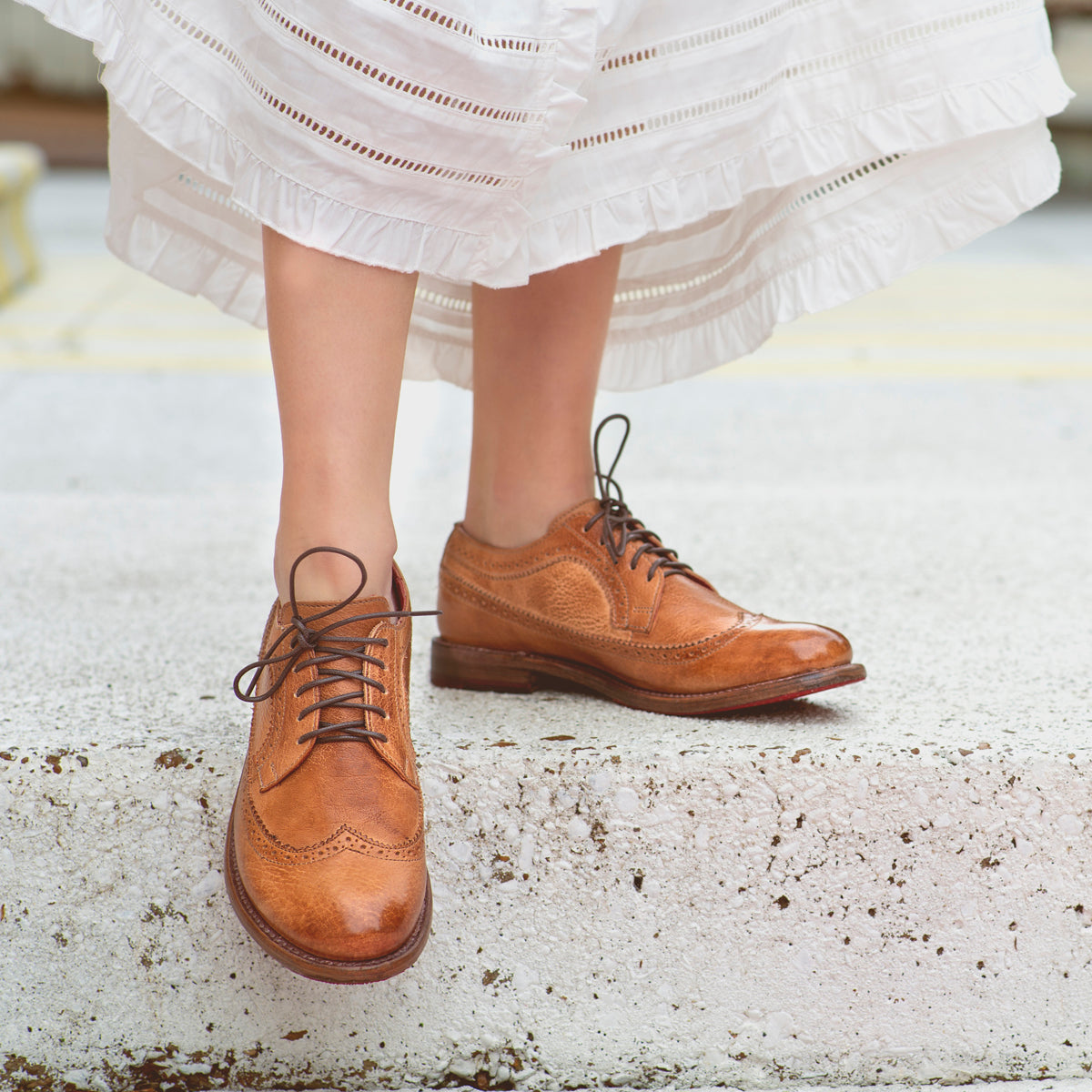A woman wearing a white dress and Bed Stu Lita K II shoes.
