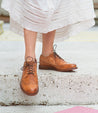 A woman wearing a white dress and Bed Stu Lita K II shoes.