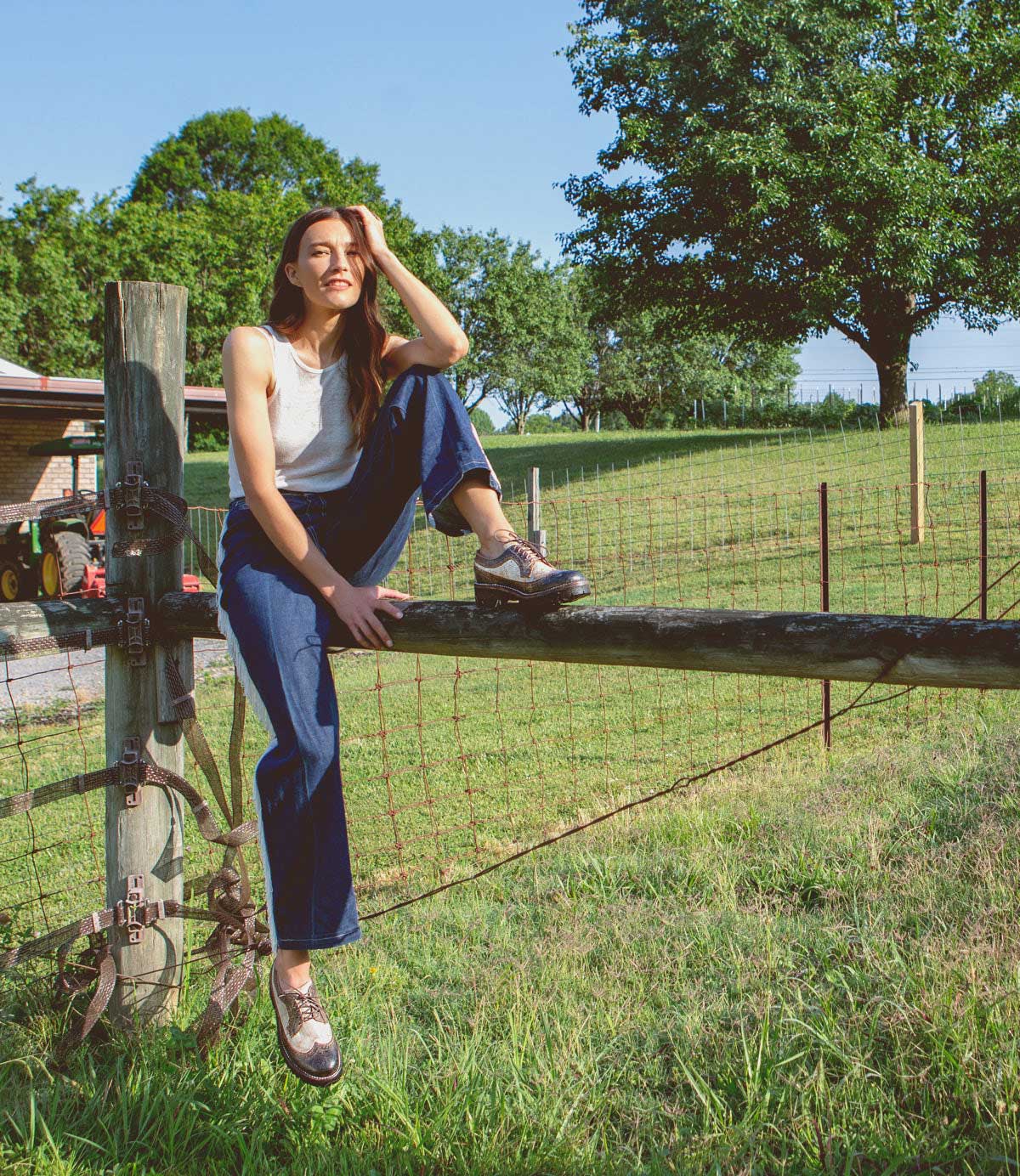 A woman sitting on a fence in a field wearing the Bed Stu Lita K III.