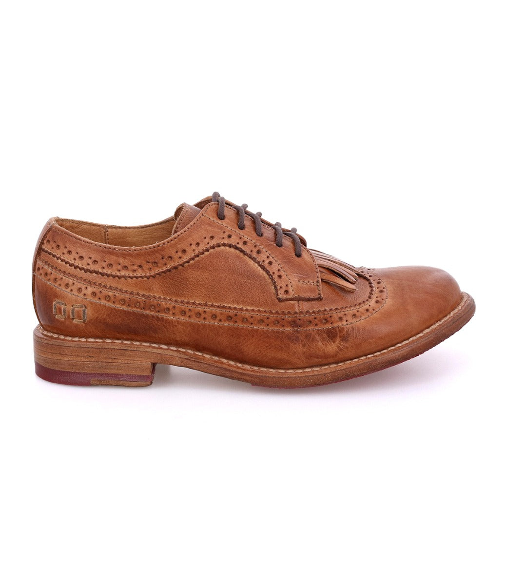 The Bed Stu Lita K is a brown leather brogue dress shoe with laces, wingtip toe, decorative perforations, and removable kiltie fringe detail, shown in side profile on a white background.