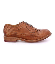 The Bed Stu Lita K is a brown leather brogue dress shoe with laces, wingtip toe, decorative perforations, and removable kiltie fringe detail, shown in side profile on a white background.