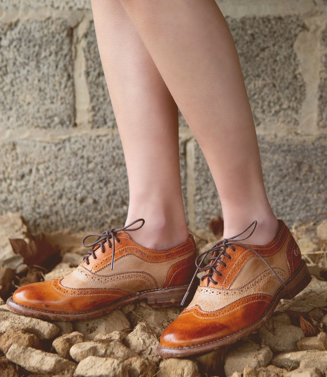 A woman wearing a pair of brown and tan Bed Stu Lita oxford shoes.