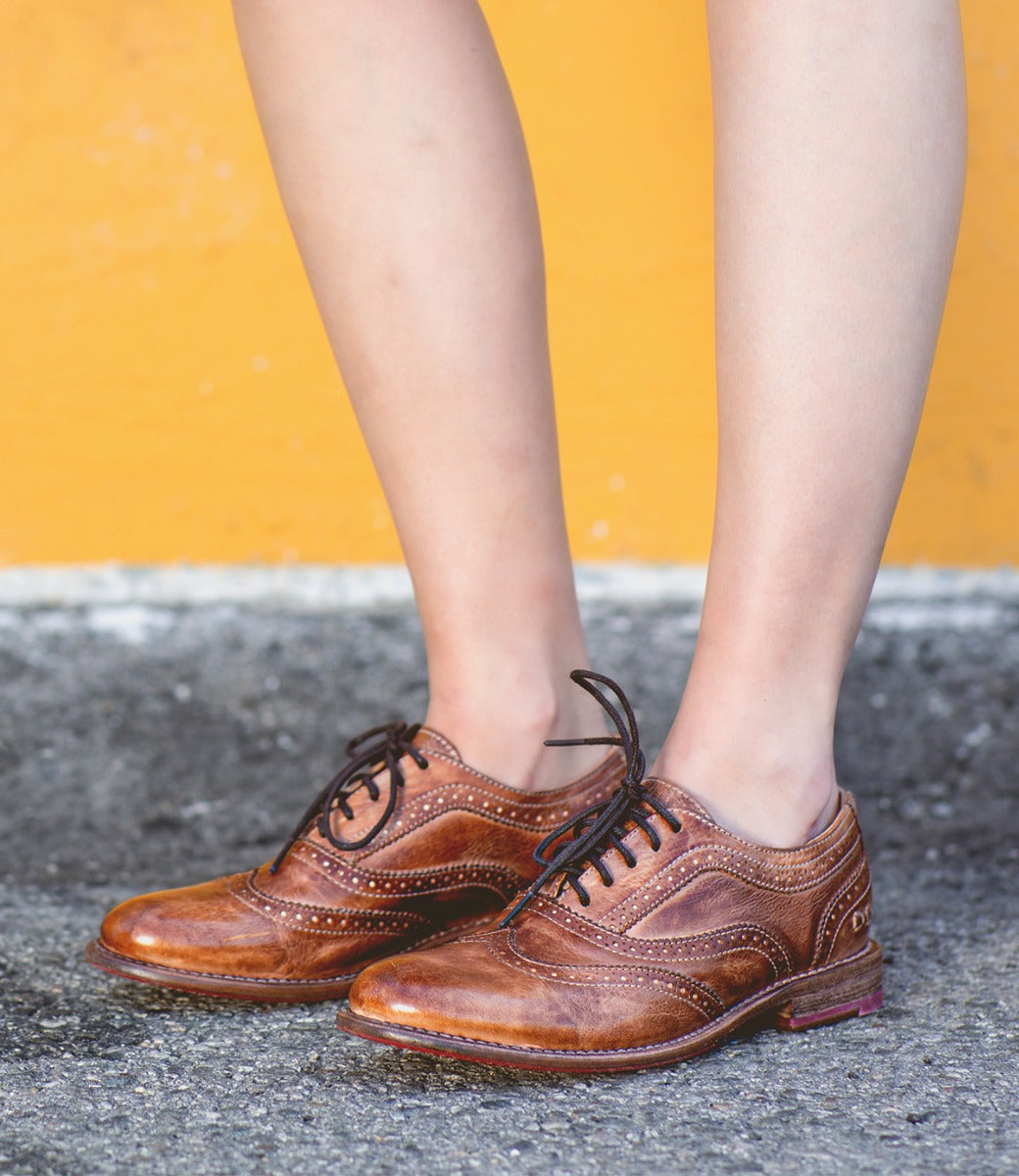 A woman wearing a pair of tan Bed Stu Lita oxford shoes.