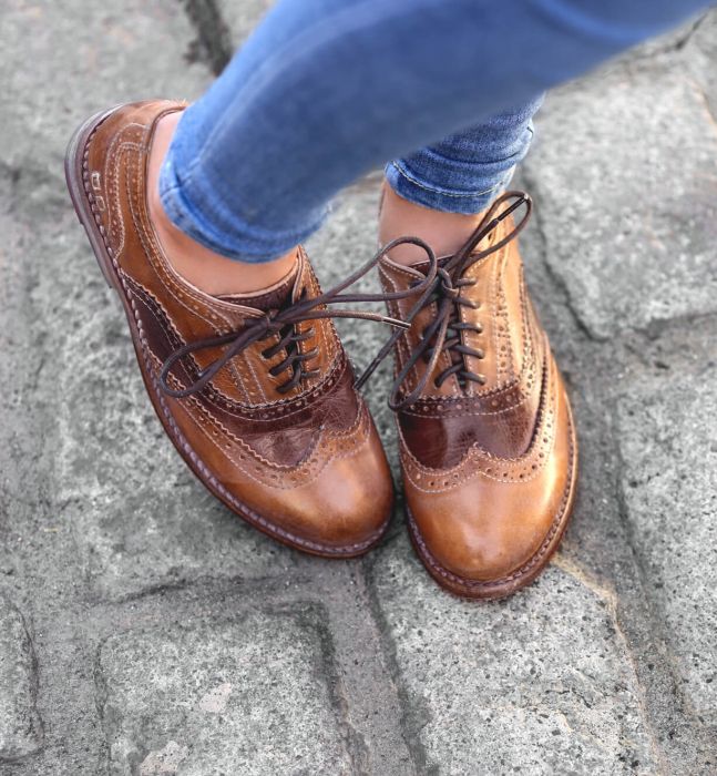 A woman wearing a pair of brown Wingtip Oxford shoes called Lita by Bed Stu.