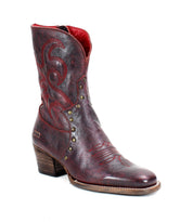 Bed Stu's "Locate" boots are crafted from brown leather and designed with flame-like stitching, metal studs, and feature a wooden heel.