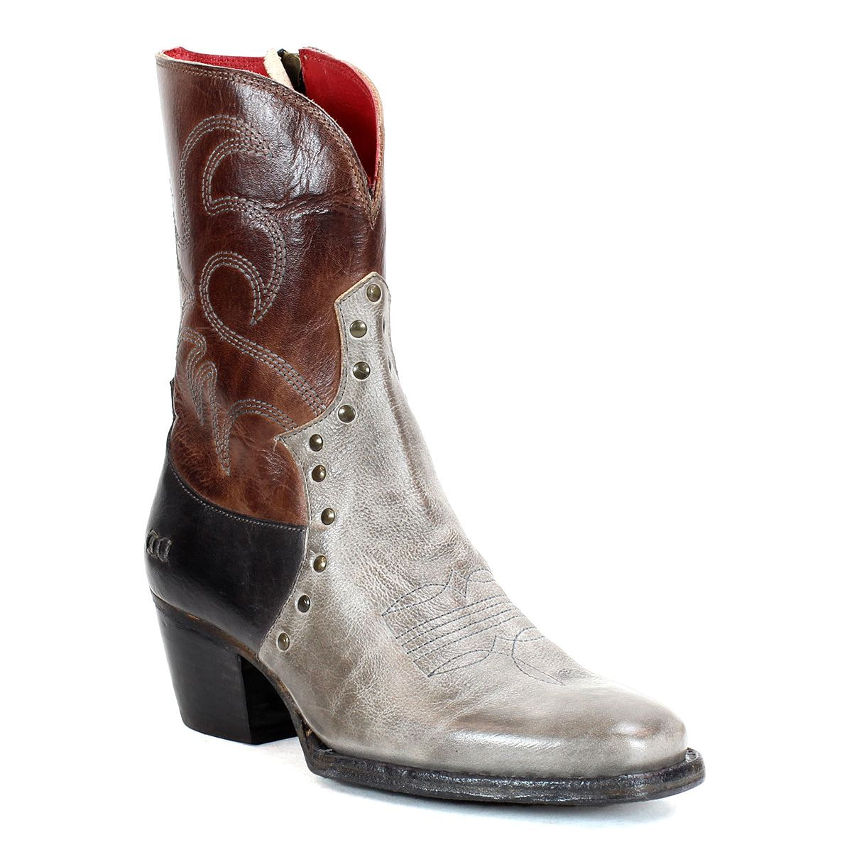 The "Locate" Western boot by Bed Stu is crafted from leather and features flame-like stitching, metallic rivets, and a side zipper. The design showcases an eye-catching blend of brown, grey, and black color blocks.