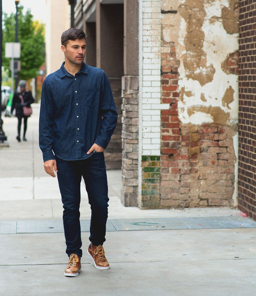 A man in a Bed Stu denim shirt walking down a sidewalk.