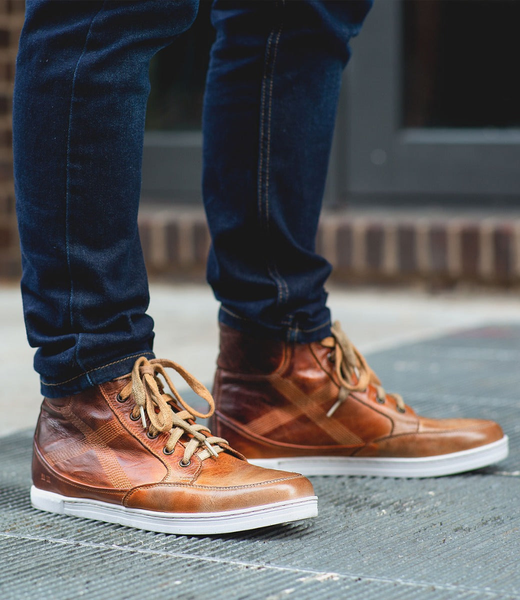 A man wearing a pair of Bed Stu Lordmind brown leather sneakers.