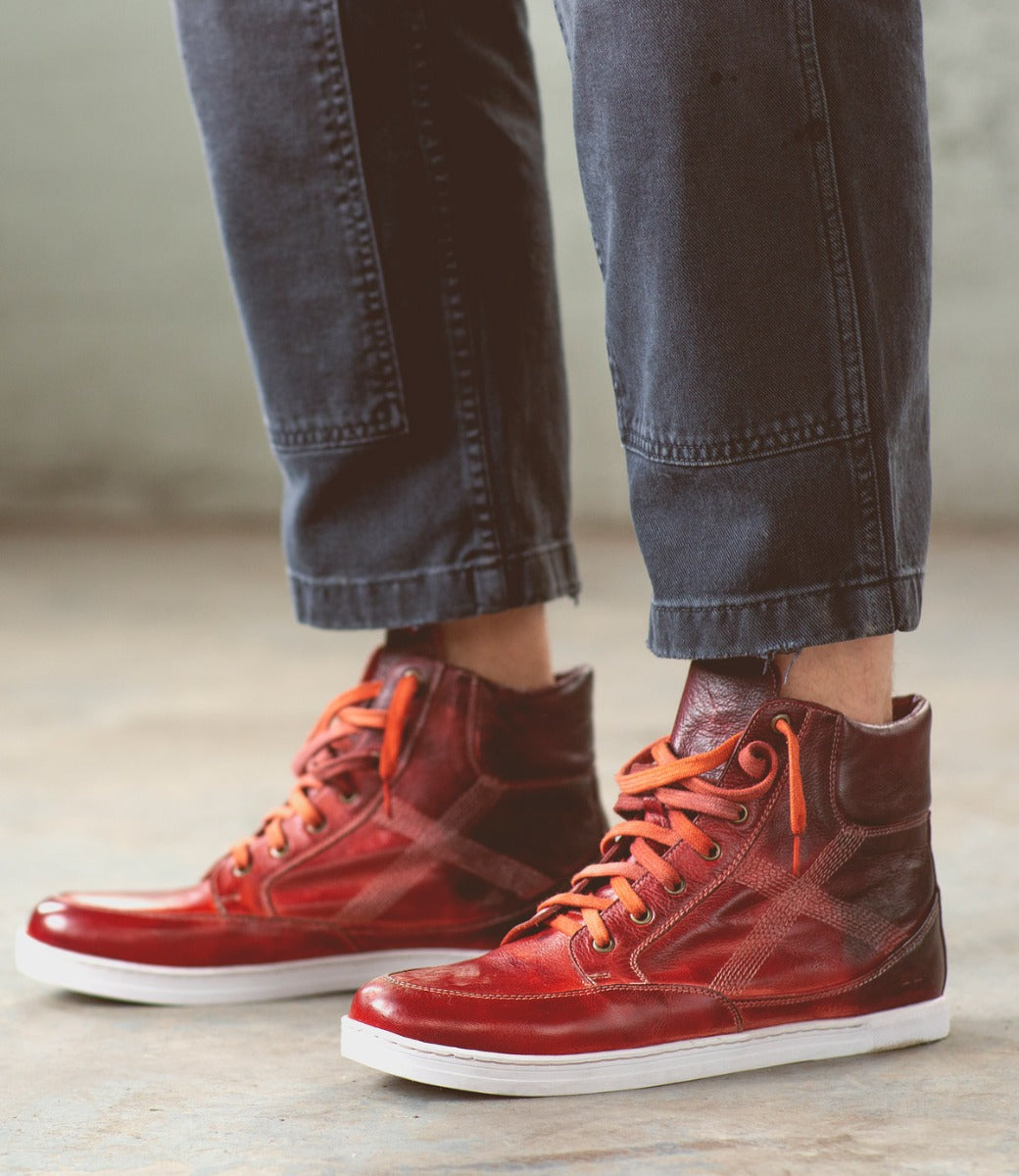 A person wearing Lordmind high top sneakers with orange laces. (Brand Name: Bed Stu)