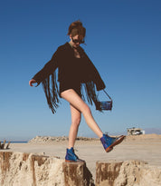 A woman is standing on a Loretta log in the desert, made by Bed Stu.