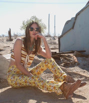 A woman sitting in the desert with a Loretta Bed Stu shoes on her feet.