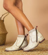 A woman wearing a pair of white Bed Stu Lotus ankle boots.