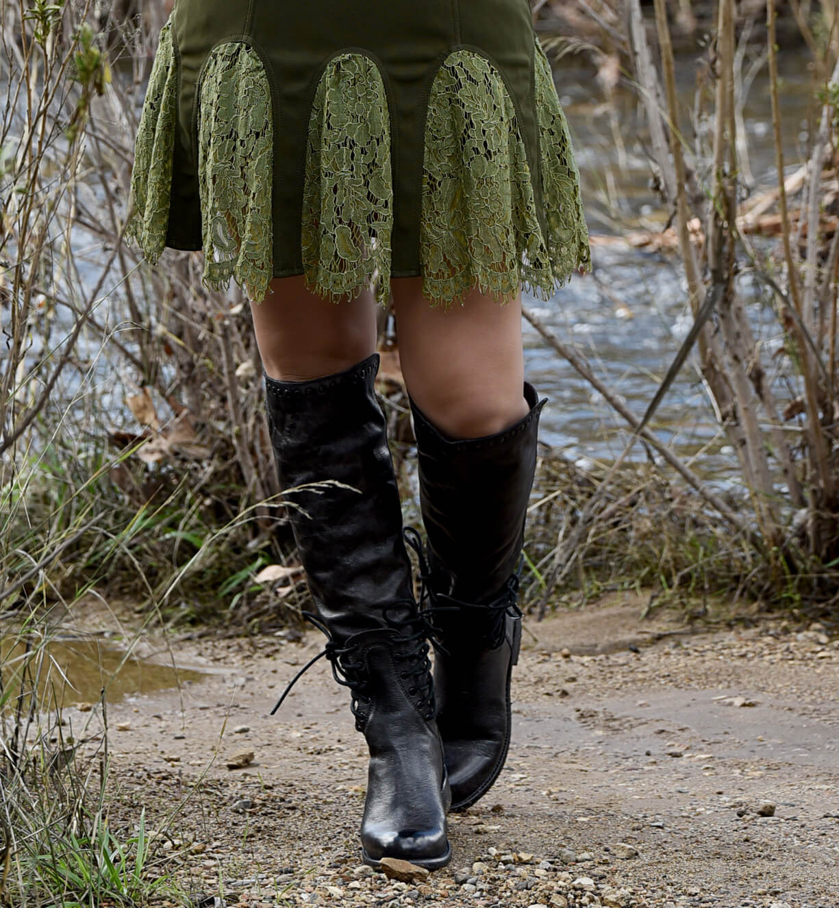 A woman in a green Loxley dress standing next to a river. Brand: Bed Stu.