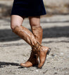 A woman wearing Bed Stu Loxley boots and a blue dress.