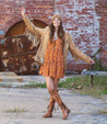 A girl wearing a Loxley dress and Bed Stu boots in front of a brick building.