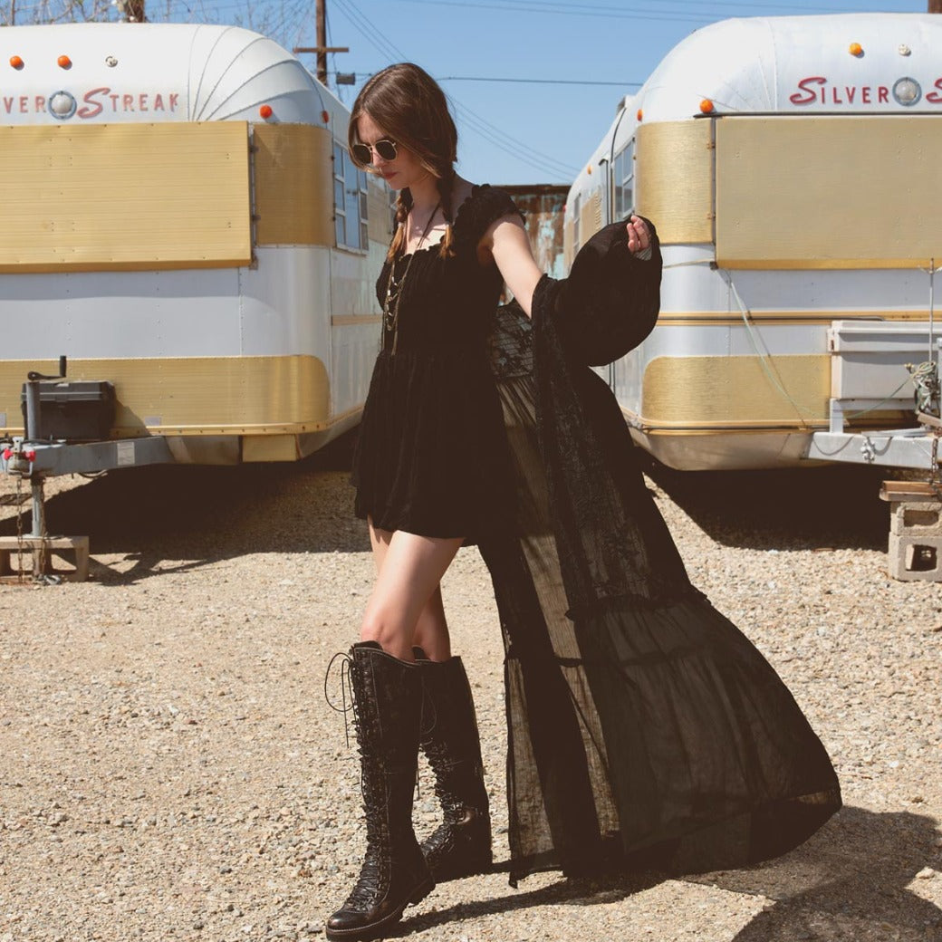 A woman in a black dress standing in front of a Bed Stu Lustrous trailer.