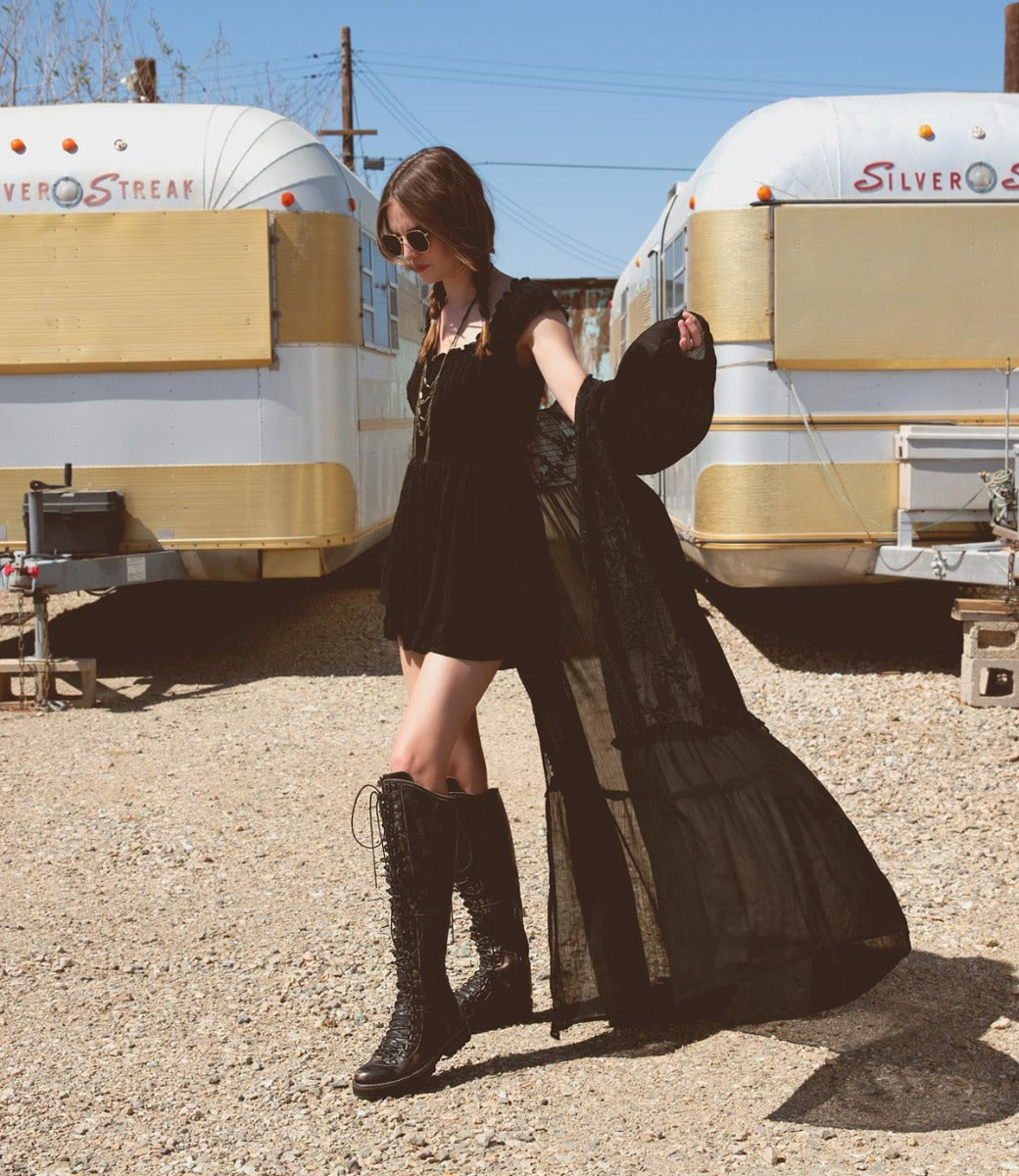 A woman in a black dress standing in front of a Bed Stu Lustrous trailer.