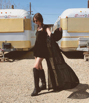 A woman in a black dress standing in front of a Bed Stu Lustrous trailer.