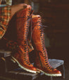 A woman in a plaid shirt is wearing a pair of Bed Stu Lustrous boots.