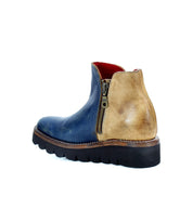 The Bed Stu Lydyi is a two-tone leather ankle boot with a blue front and tan back, featuring a side zipper, thick rubber sole, and cushioned breathable insole.
