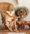 A woman is sitting on a wooden chair wearing a pair of Bed Stu Lydyi boots.