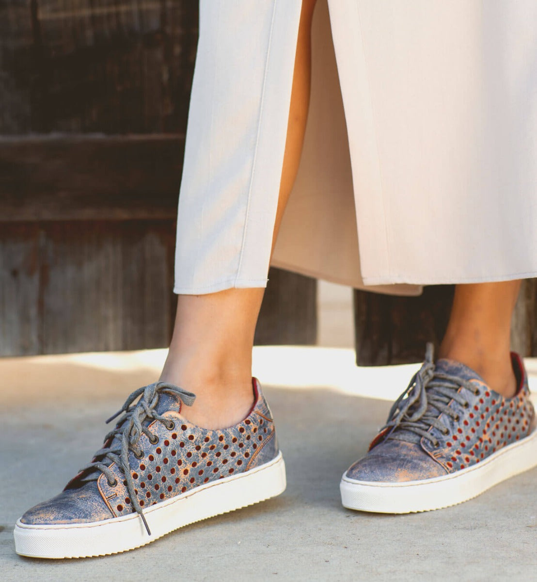 A woman wearing a pair of Bed Stu Lyne sneakers and a white skirt.