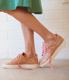 A woman in a green dress and pink Bed Stu sneakers.