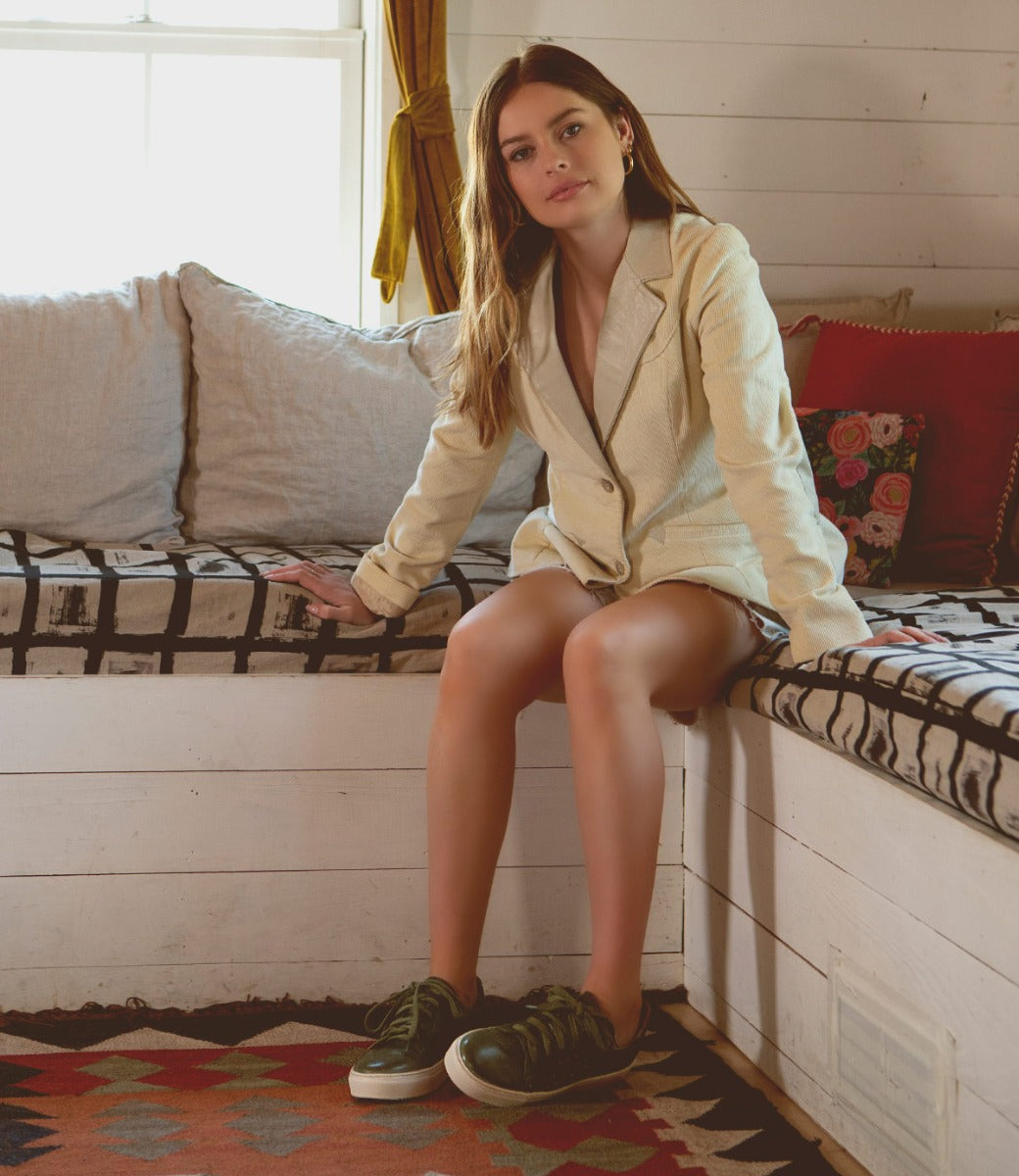 A woman sitting down wearing Bed Stu sneakers.