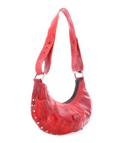 The Madre by Bed Stu is a red leather hobo bag featuring metal studs and an adjustable strap, perfect for adding a rock ‘n’ roll edge to your style.
