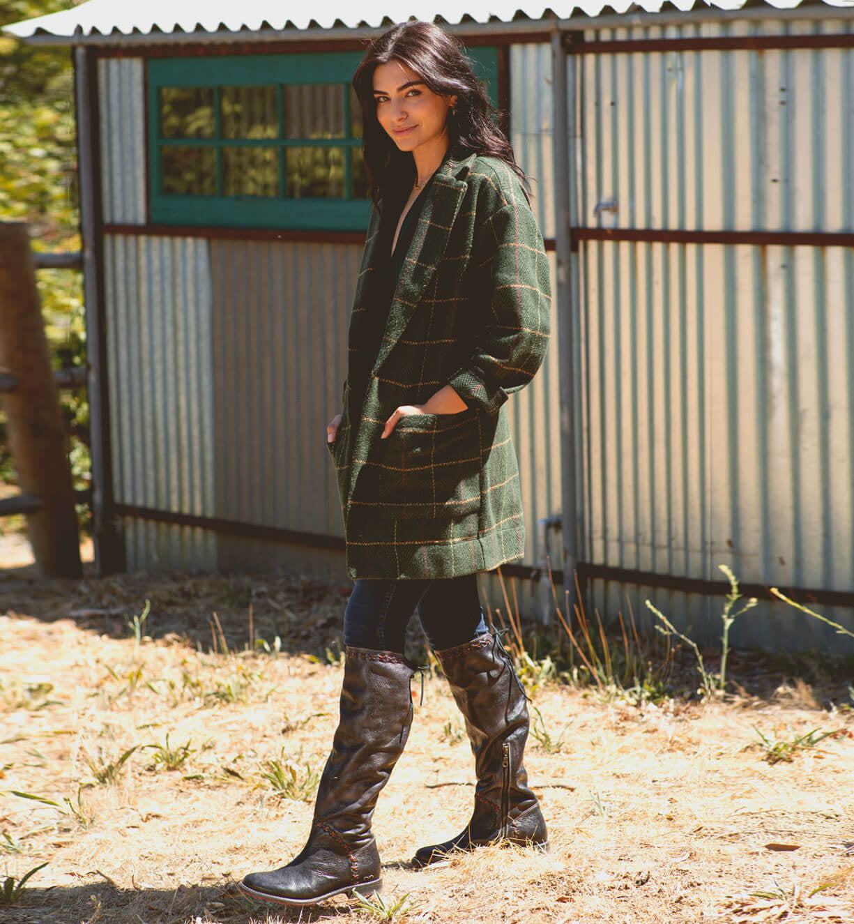 A woman in a green plaid coat standing in front of a Bed Stu Manchester III shed.