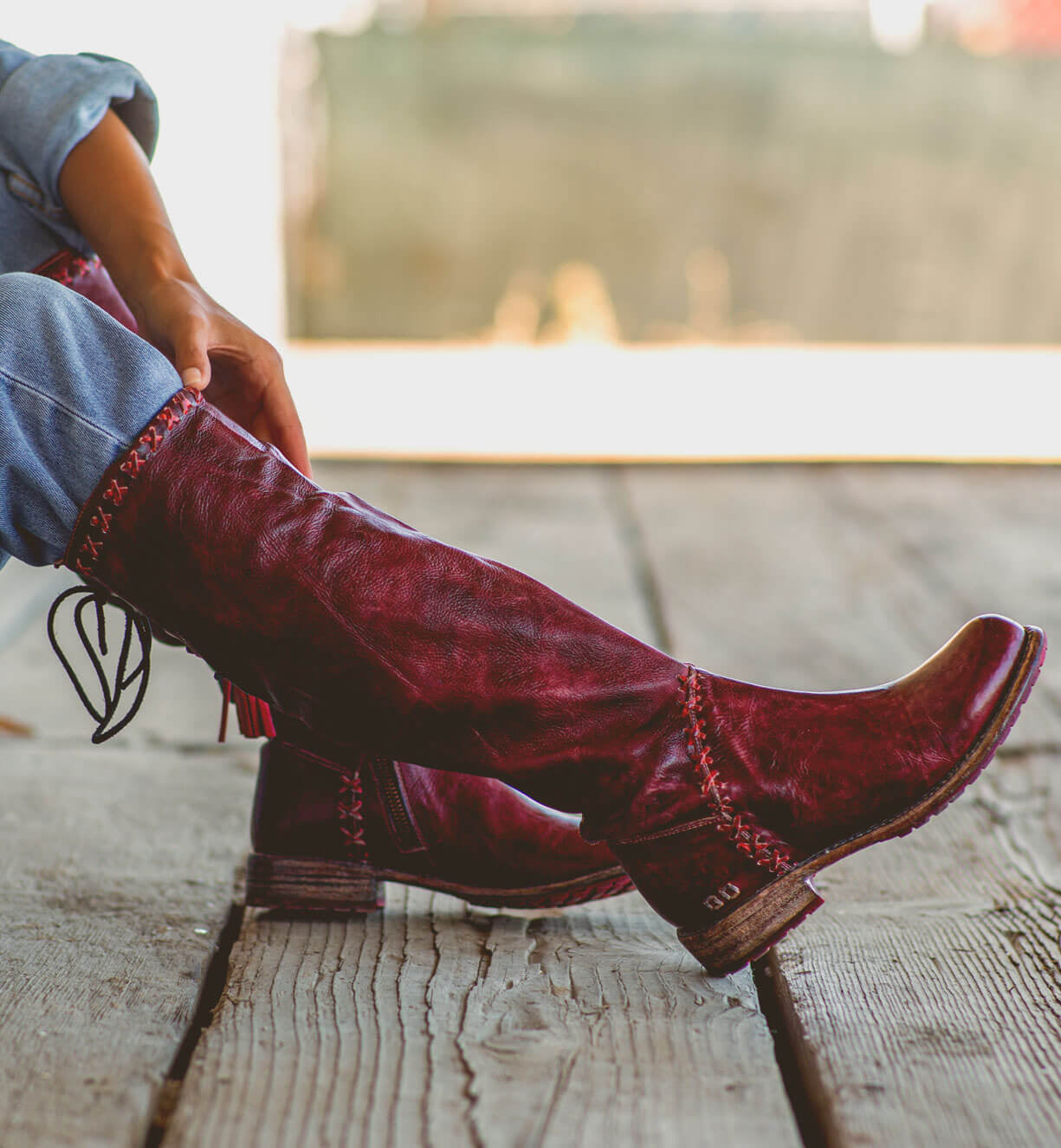 A woman wearing a pair of Bed Stu Manchester III boots on a wooden deck.
