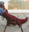 A woman wearing a pair of Bed Stu Manchester III boots on a wooden deck.