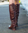 A woman's legs in a pair of Bed Stu Manchester brown leather boots.