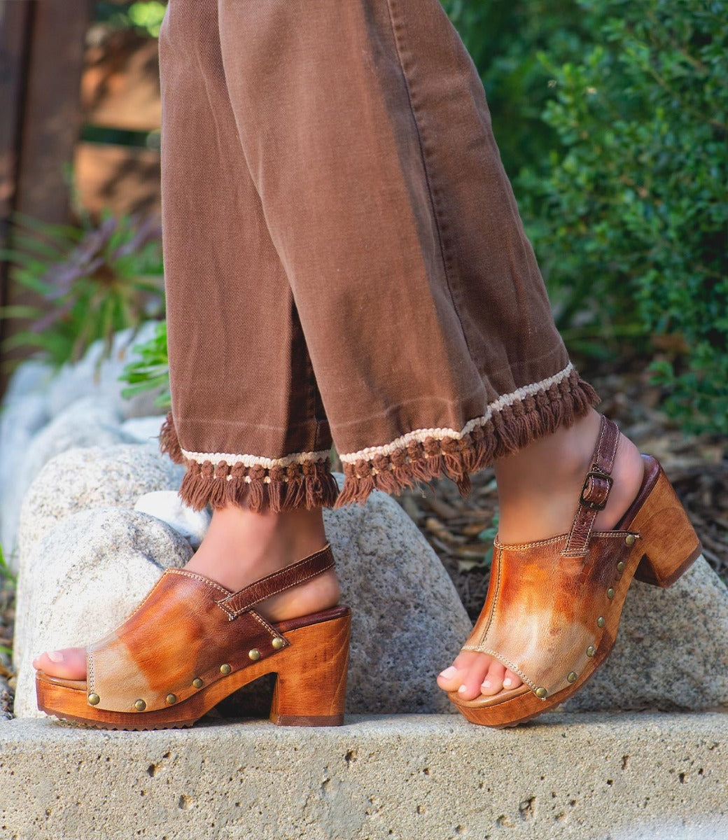 A woman wearing brown pants and Marie sandals by Bed Stu.