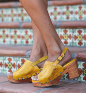 A woman wearing yellow Bed Stu Marie sandals on a set of steps.