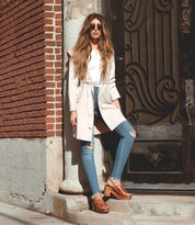A woman in jeans and trench coat wearing Marie sandals from Bed Stu