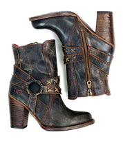 A pair of black distressed leather boots with a high heel, red stitching and o-ring harness. on the profile view. 