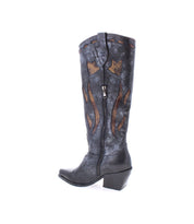 The Meadow boot by Bed Stu is a single black leather cowgirl boot featuring decorative brown flame patterns, floral inlay designs, and a zipper on the side, set against a white background.