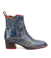 The Merryli by Bed Stu is a stylish blue leather ankle boot featuring a brown stacked heel, red interior lining, and a cushioned insole for all-day comfort.