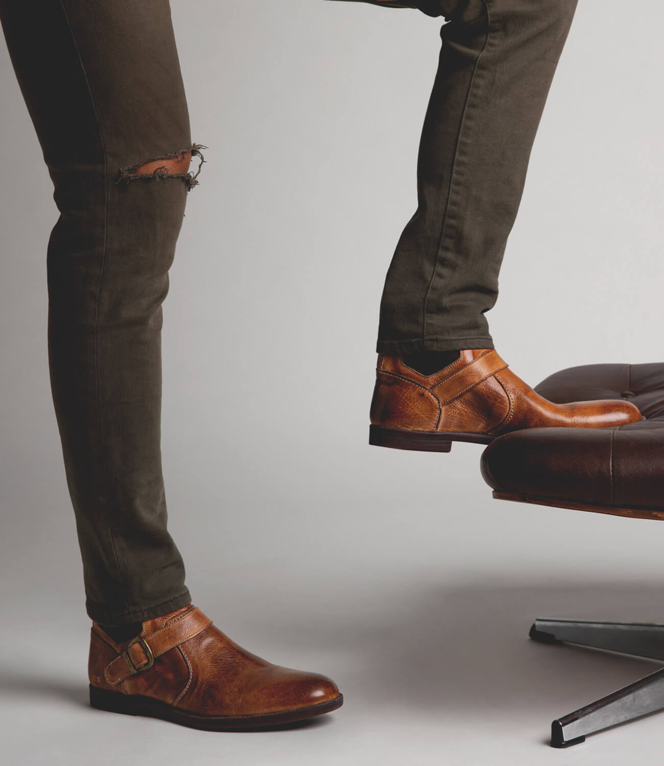 A man standing on a chair wearing Bed Stu Michelangelo brown leather shoes.