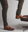 A man standing on a chair wearing Bed Stu Michelangelo brown leather shoes.