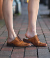 A woman wearing a pair of Bed Stu Mickie shoes on a brick sidewalk.