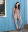 A woman leaning against a wall in a beige Bed Stu sweater and khaki pants named Mickie.