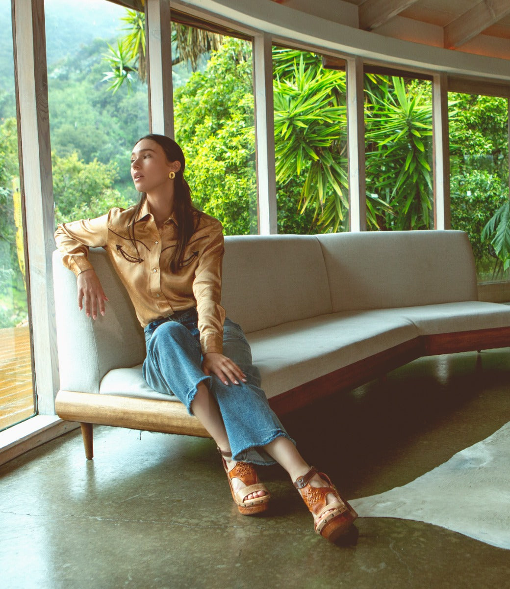 A woman sitting on a Millennial couch in a living room, made by Bed Stu.