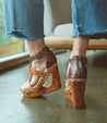 A woman's feet in a pair of Bed Stu Millennial wooden wedges.