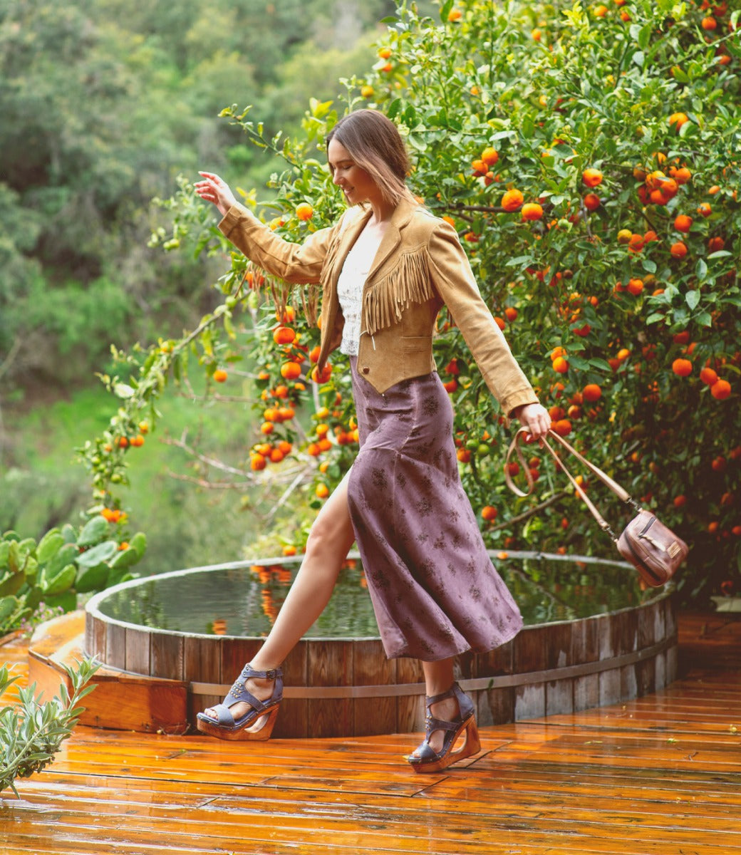 A woman walking on a Millennial deck with an orange tree in the background. Brand name: Bed Stu.